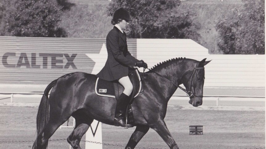 A black and white photo of a dressage horse ridden by a young woman circa 1980s.
