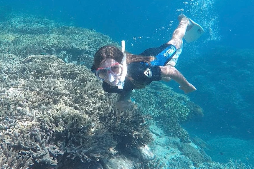 Young boy snorkelling underwater next to reef
