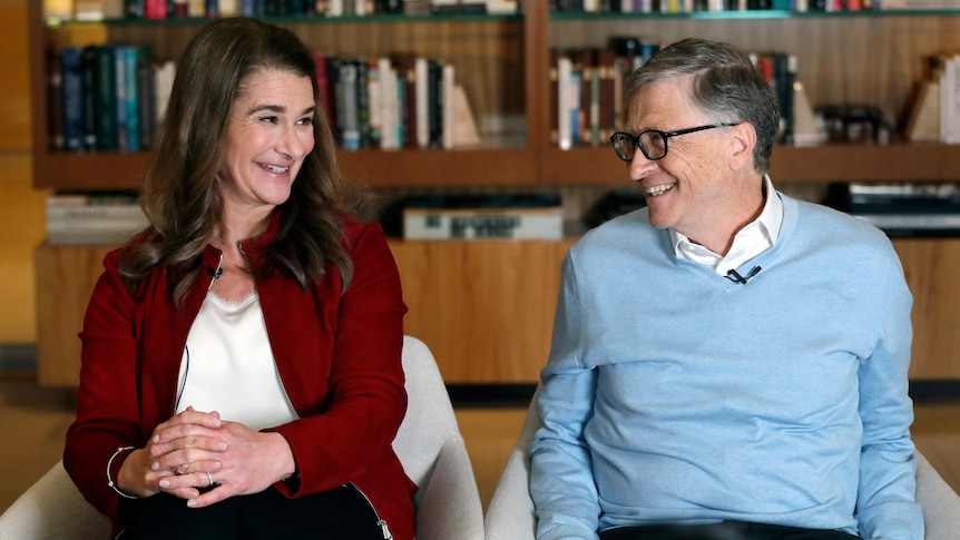 Melinda Gates smiles at Bill Gates, who is sitting next to her. 