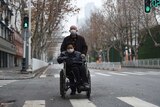 A man wearing a face mask pushes a woman on a wheelchair in Wuhan.