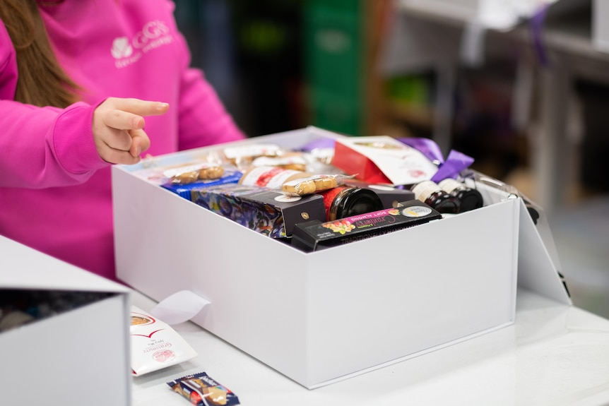 A box filled with food like jams, biscuits and chocolate.