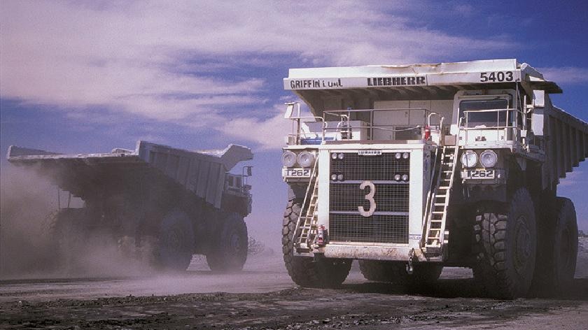Two coal trucks pass each otheropen-cut mine.