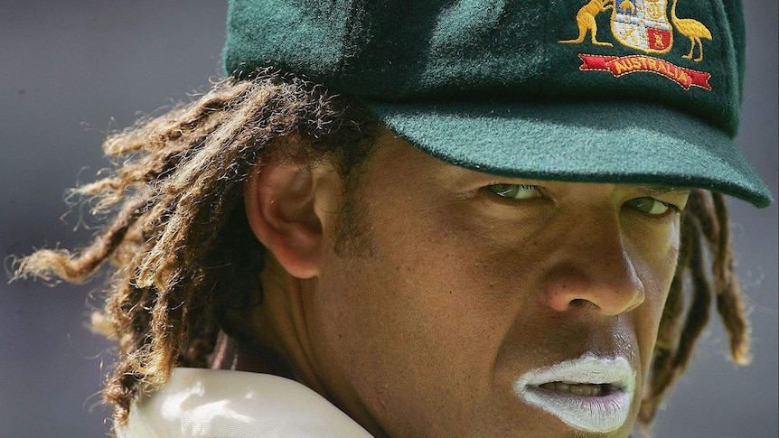 A close up photograph of Andrew Symonds, wearing baggy green cap and white sunscreen lips, looking focussed