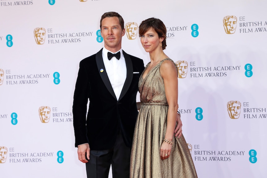 Benedict Cumberbatch wears a suit with a bow tie and Sophie Hunter in a golden gown with a braided belt.