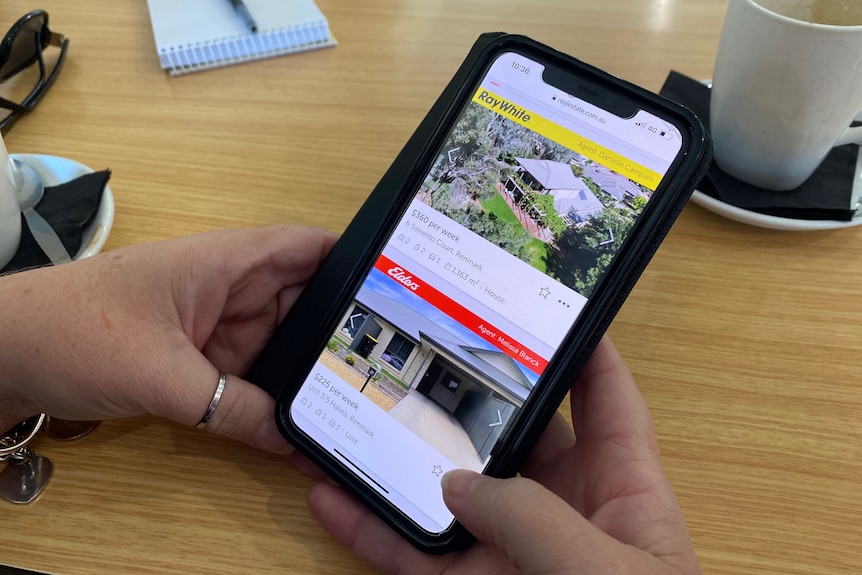 woman using her iphone to scroll through house listings on real estate.com