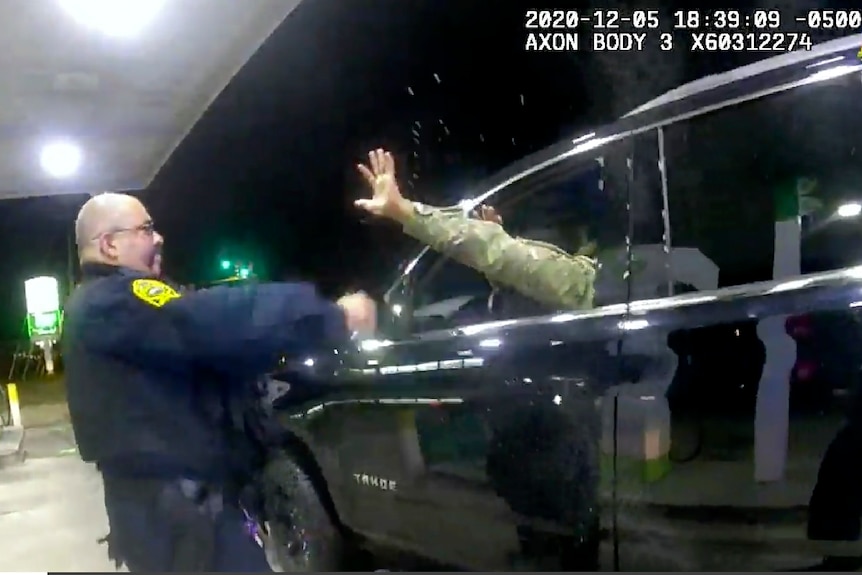Police officer points spray gun at driver