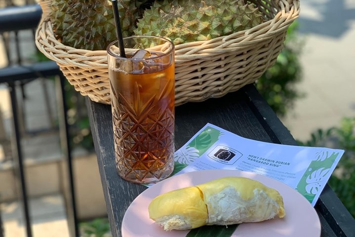 Durian fruit sits on a plate beside a drink.