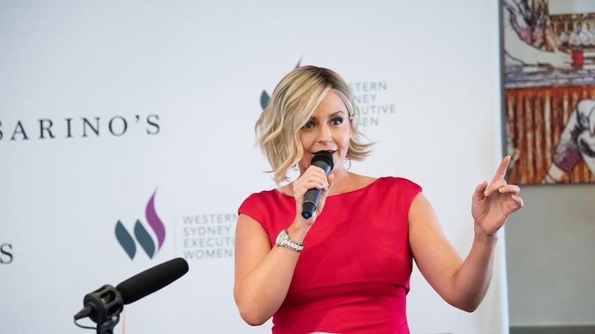 Businesswoman Amanda Rose holding a microphone and speaking at an event.