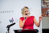 Businesswoman Amanda Rose holding a microphone and speaking at an event.