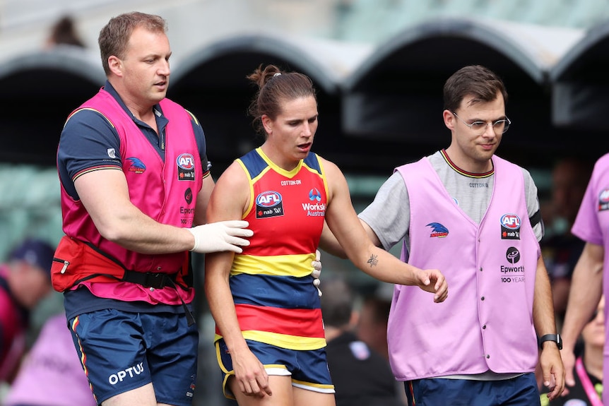 Chelsea Randall is attended to and escorted off the field by medical staff. 