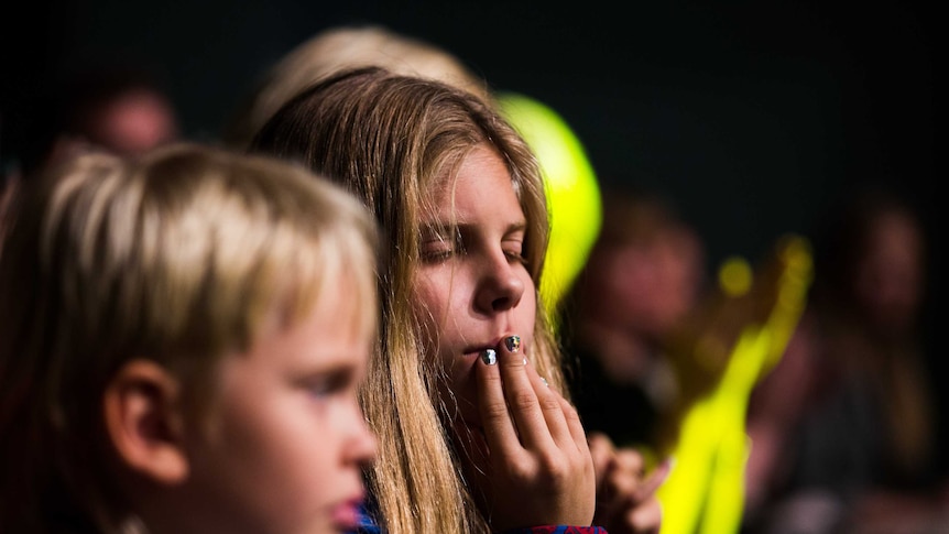 A girl listens to music at a concert with her eyes closed.
