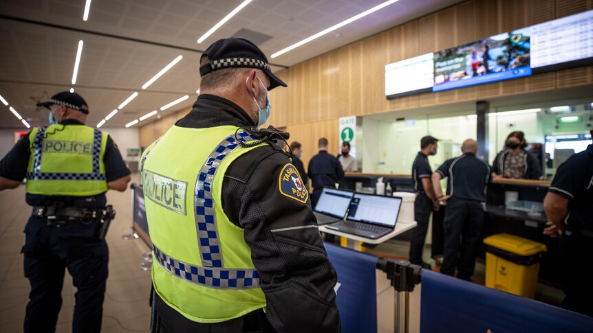 two police officers in high vis, shown side-on and back-on, at Hobart Airport 