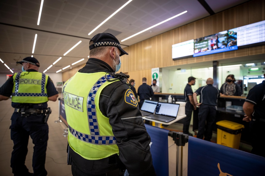 two police officers in high vis, shown side-on and back-on, at Hobart Airport 