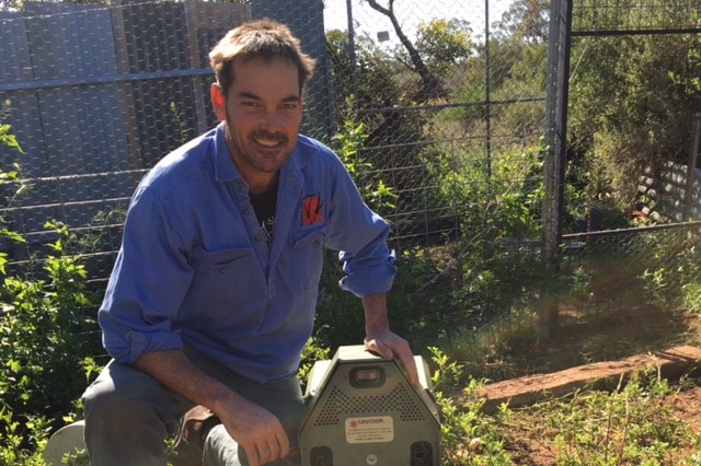 Dr John Read crouches in a garden bed