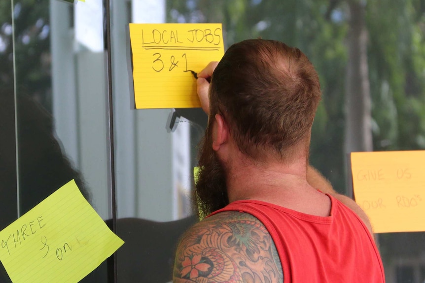 An INPEX worker writes his concerns on a note stuck on the window at the JKC office in Darwin.