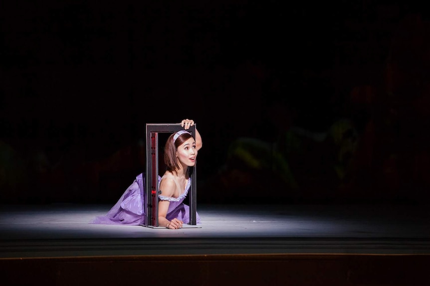 A female ballet dancer in a blue dress, performing on stage