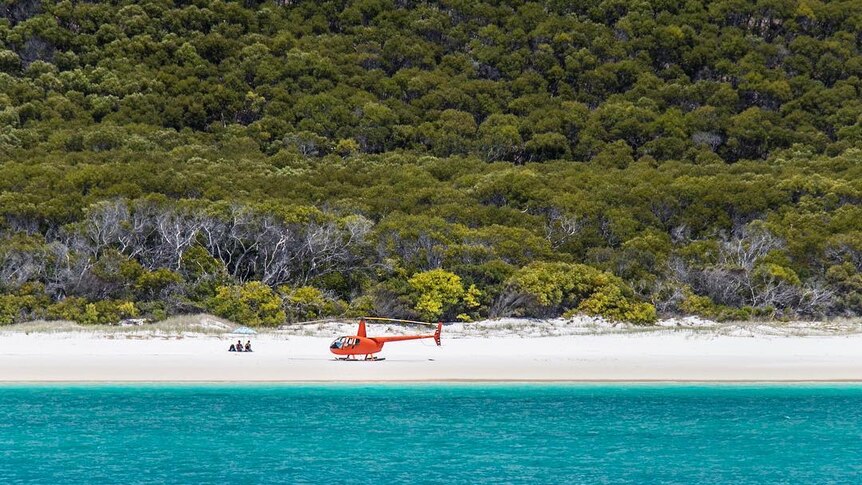 An aerial shot of a helicopter landed on Whitehaven Beach, Qld