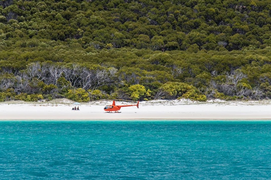 An aerial shot of a helicopter landed on Whitehaven Beach, Qld