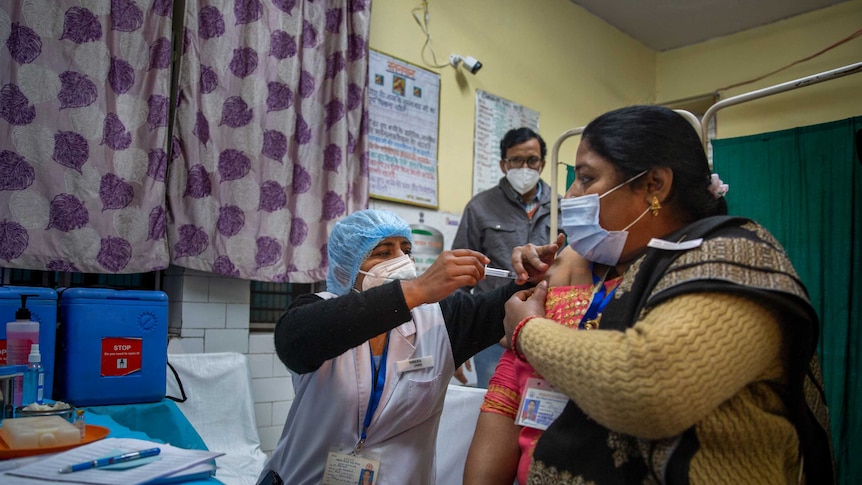 An Indian health worker gives a woman a vaccination