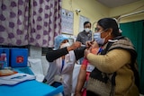 An Indian health worker gives a woman a vaccination