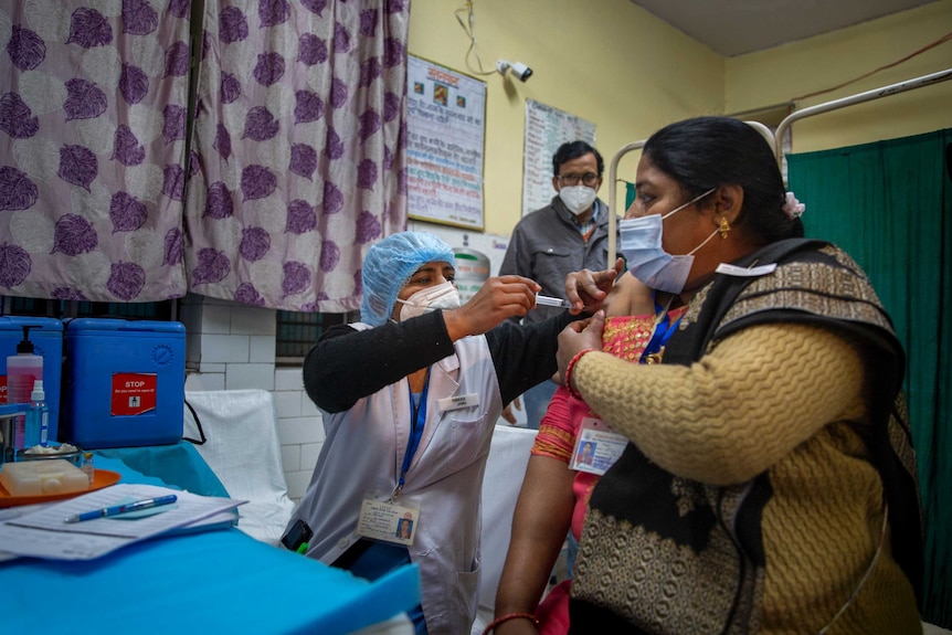 An Indian health worker gives a woman a vaccination