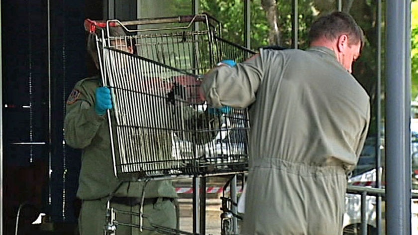 Bomb squad members carry a trolley out of a Darwin shopping centre