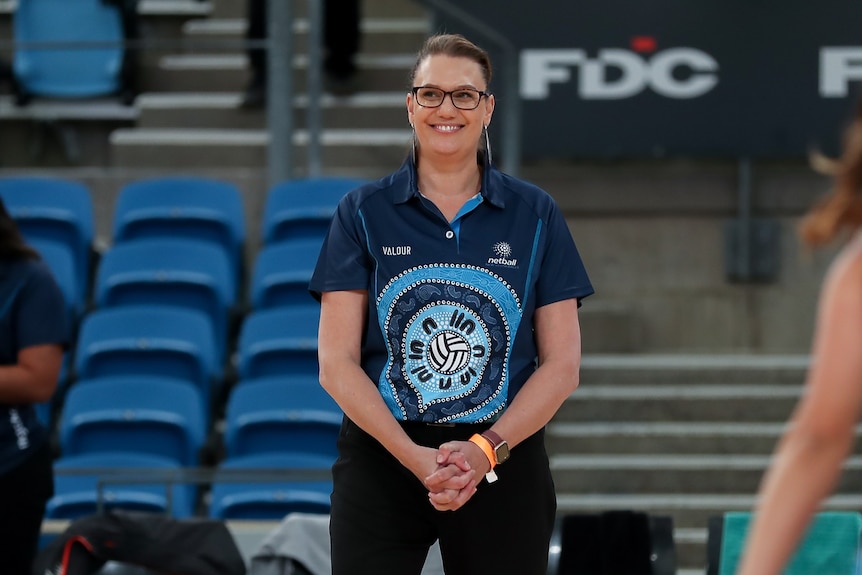 Netball coach Ali Tucker-Munro stands and smiles.