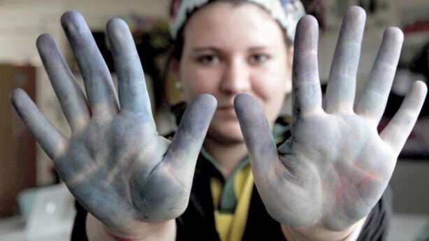 Teenage girl holds up hands to show stained palms