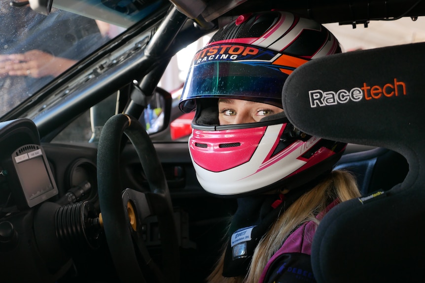 Close-up of woman's face wearing racing helmet.