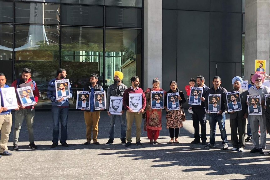 Group of supporters holding photos of Manmeet Alisher outside the Supreme Court in Brisbane.