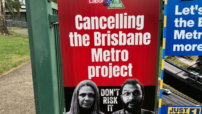 A signs says "cancelling the Brisbane Metro project, don't risk it" with faces of local election candidates.