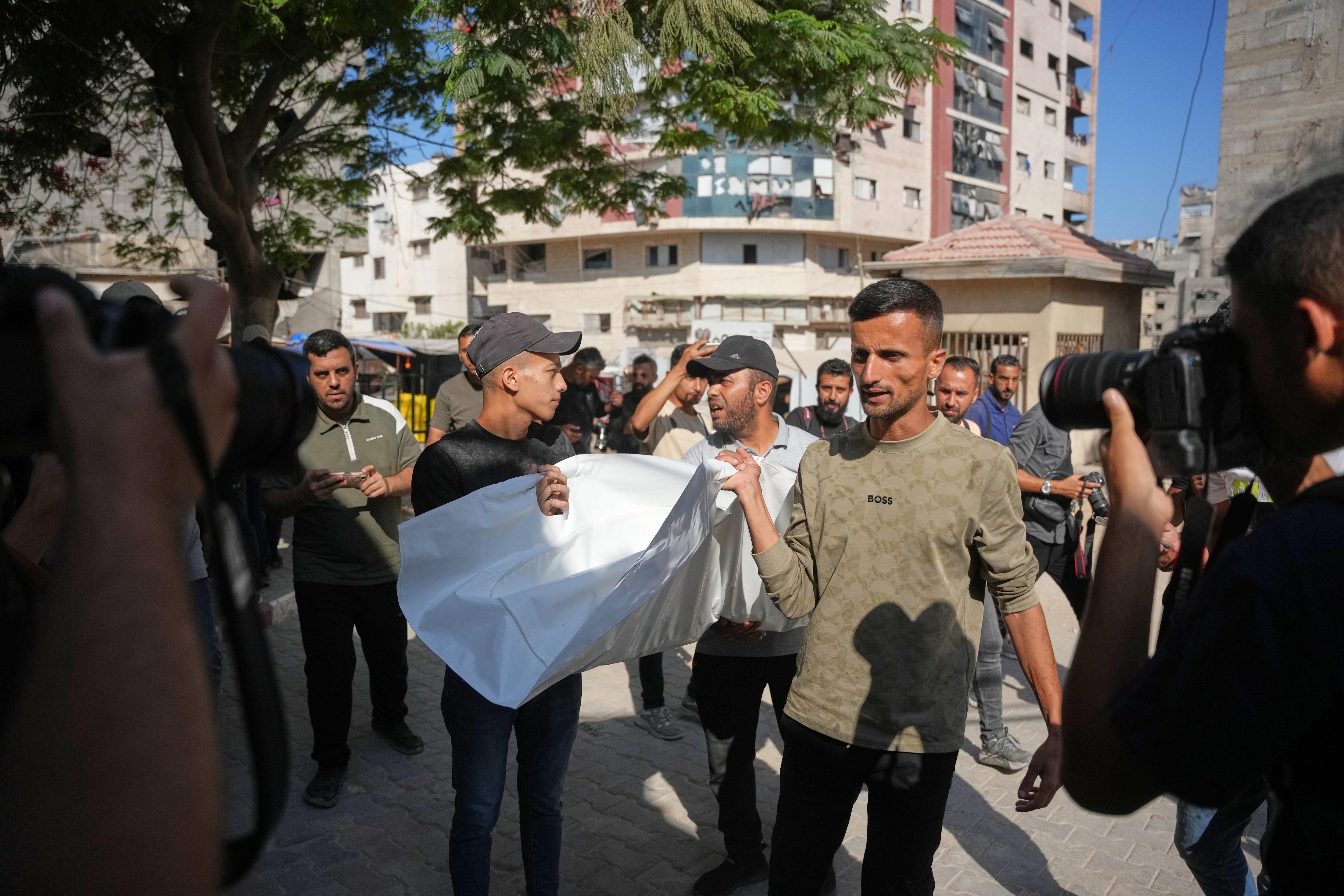 A group of men carry a white body bag