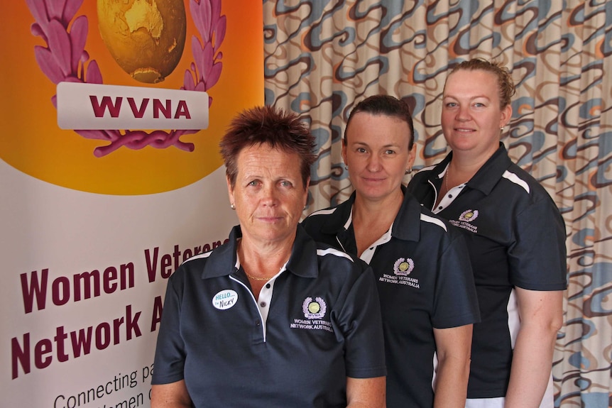 Three women stand in front of a Women Veterans Network sign