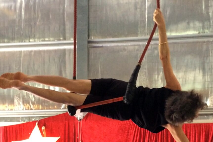 Woman balancing lying sideways on a trapeze
