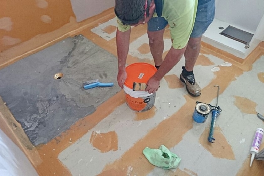 Man bending over while tiling a floor