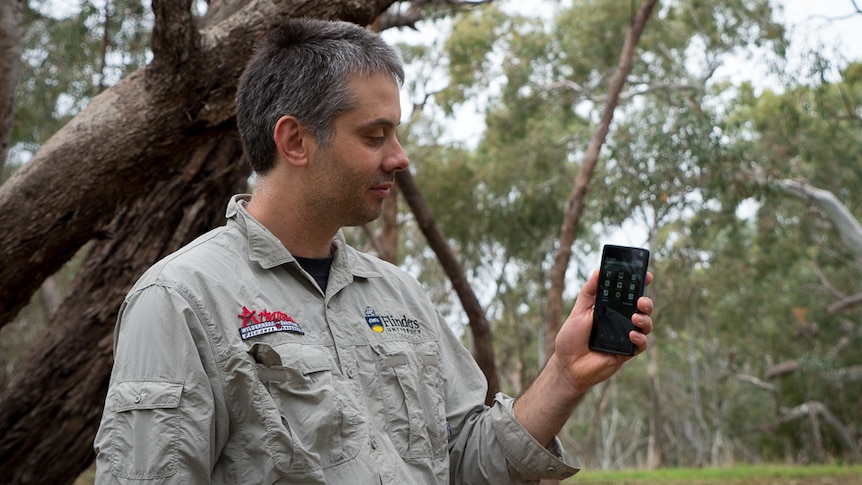 App creator Dr Paul Gardner-Stephen holding mobile phone.