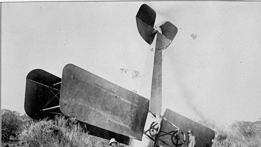 Old picture of Kalgoorlie built biplane crashed on it's nose in bushland.