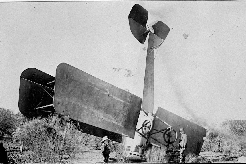 Old picture of Kalgoorlie built biplane crashed on it's nose in bushland.