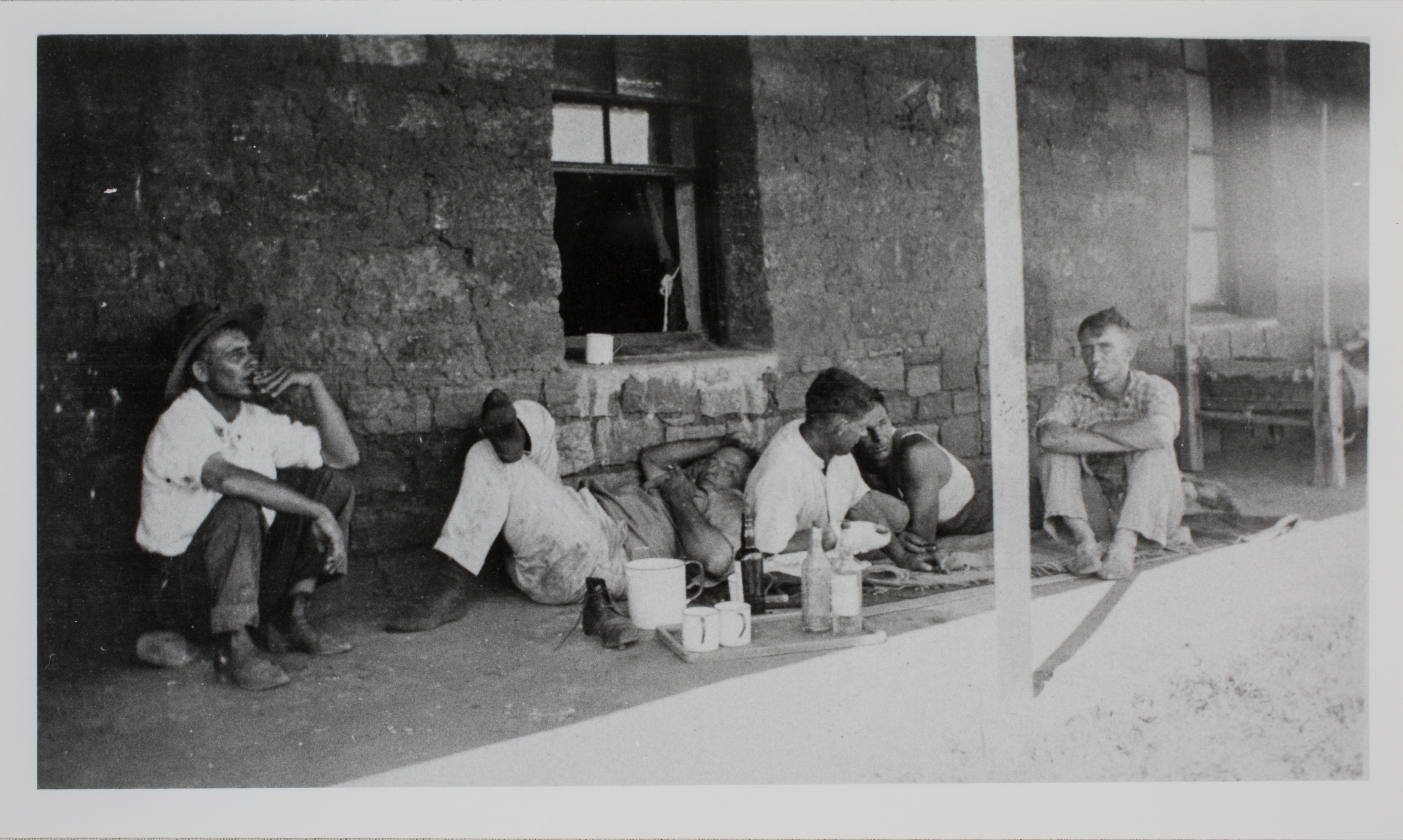 Men sitting on the verandah of a building.