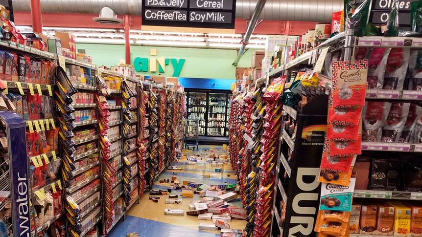 Groceries in a shop lie on the aisle floor.