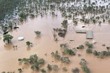 An aerial photo of a shed and tank surrounded by brown flood waters.