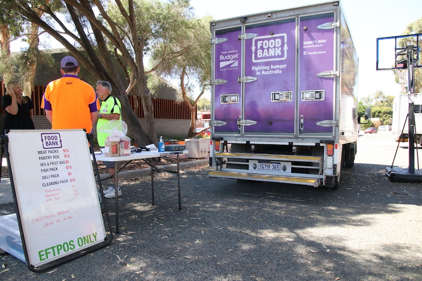 A purple Foodbank truck pictured next to a menu and two volunteers