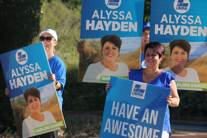 WA Liberal MP Alyssa Hayden pictured campaigning with a Liberal supporter standing in front of election posters.