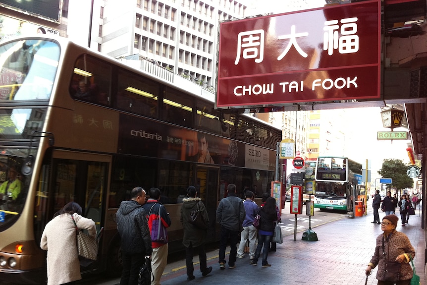 a busy hong kong street showing a chow tai fook sign