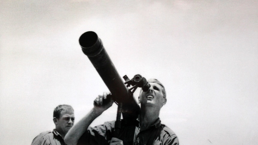 A man looks through the eyepiece of a large gun during the Vietnam War.