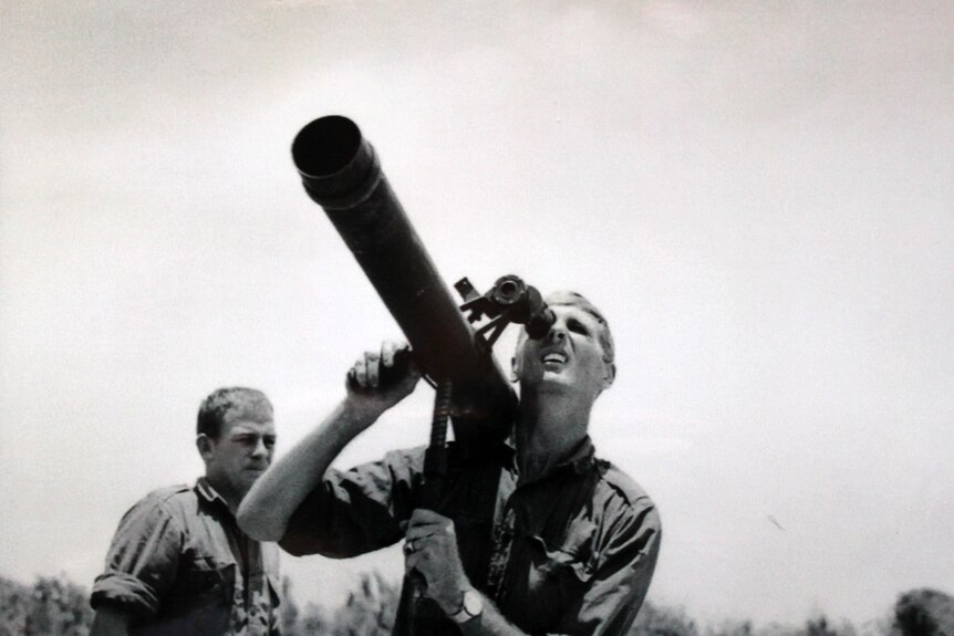 A man looks through the eyepiece of a large gun during the Vietnam War.