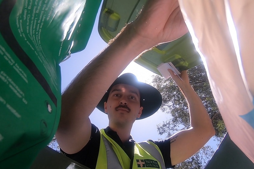 A man peers into a garbage bin