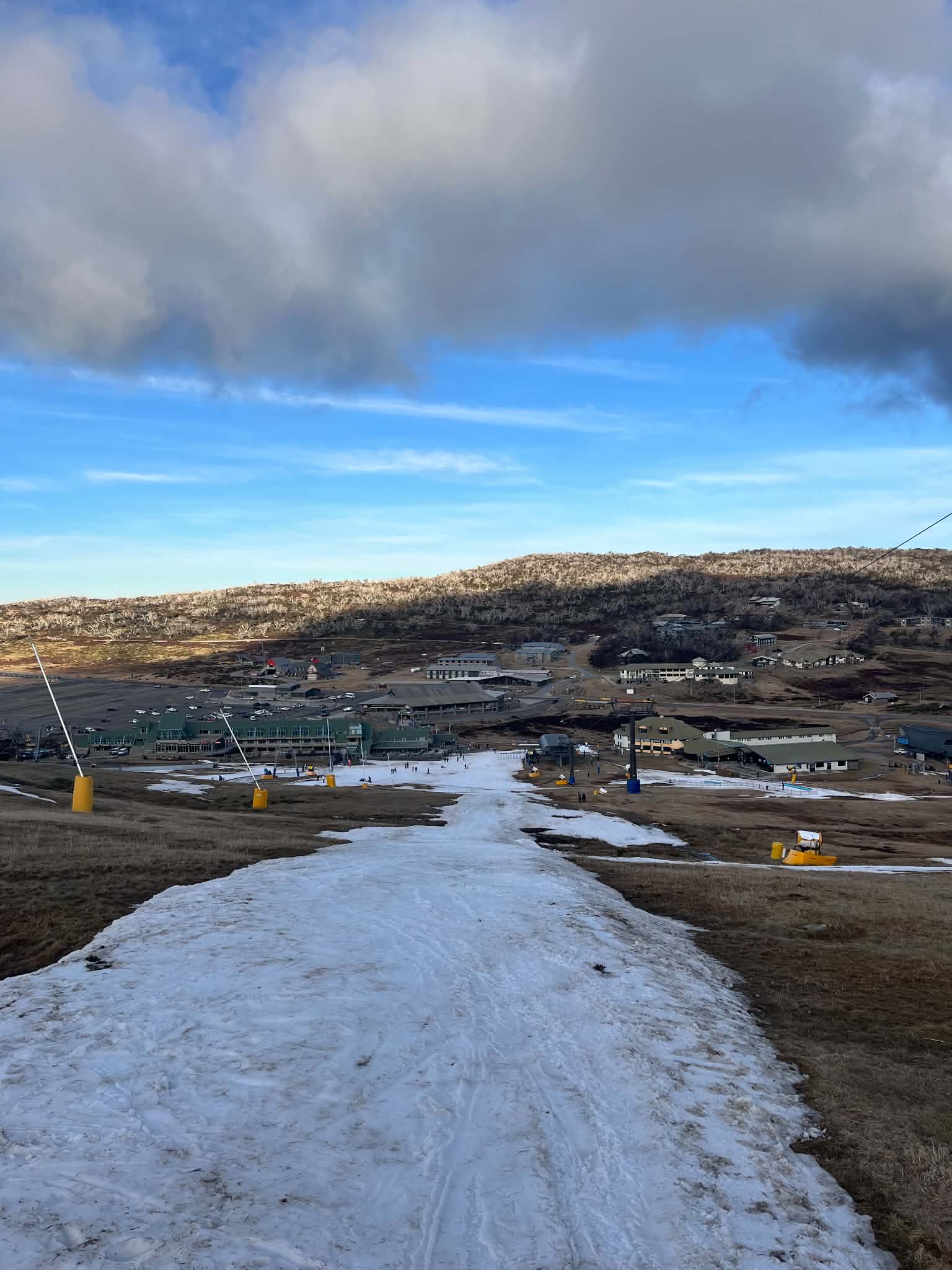 View looking down mountain covered with patches of snow
