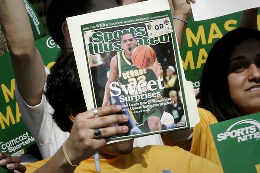 A George Mason University fan holds up the cover of Sports Illustrated magazine.