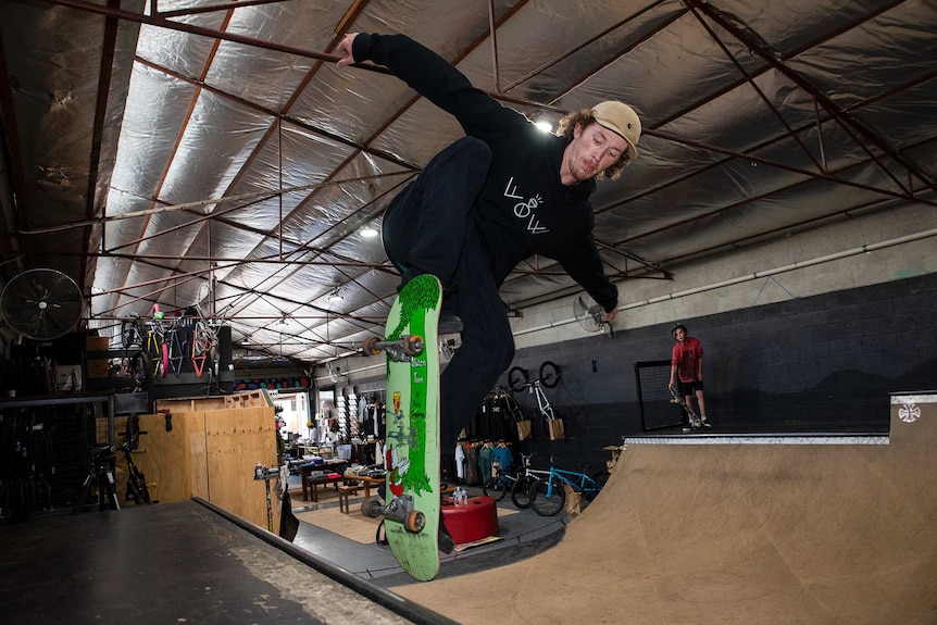 A skateboarder lifts off the edge of an indoor ramp.